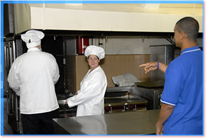 The Person in Charge directing two chefs in a kitchen