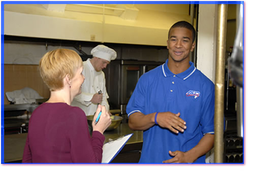 Health inspector talking to a Person In Charge in a commercial kitchen. 