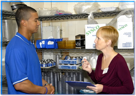 Health inspector talking to a PIC in a commercial kitchen.