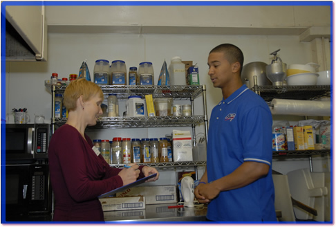 Health inspector talking to a Person in Charge in a commercial kitchen.