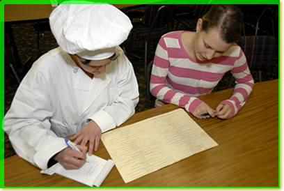 A chef and another woman going over a menu together.