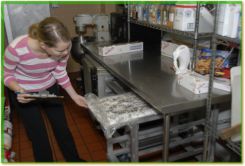 A woman with a clipboard inspecting food.