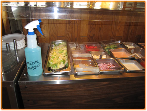 A sanitizer bottle sitting on a salad bar.