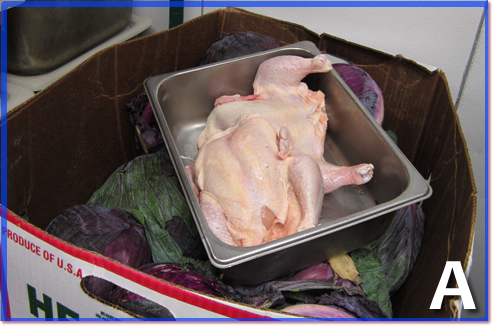 A container of raw chicken sitting on top of a box of cabbage.