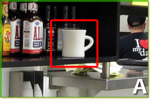 A storage shelf full of supplies and a white coffee cup.