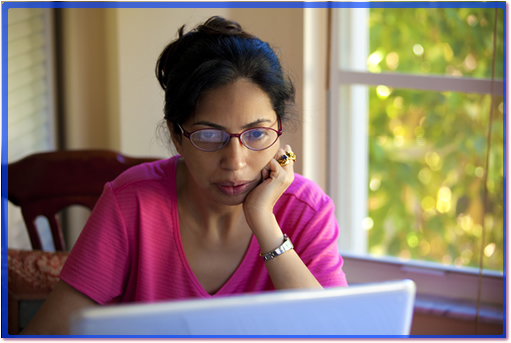 A woman working on her laptop, thinking.